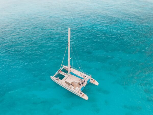 Stunning aerial view of a catamaran sailing in crystal clear turquoise waters.